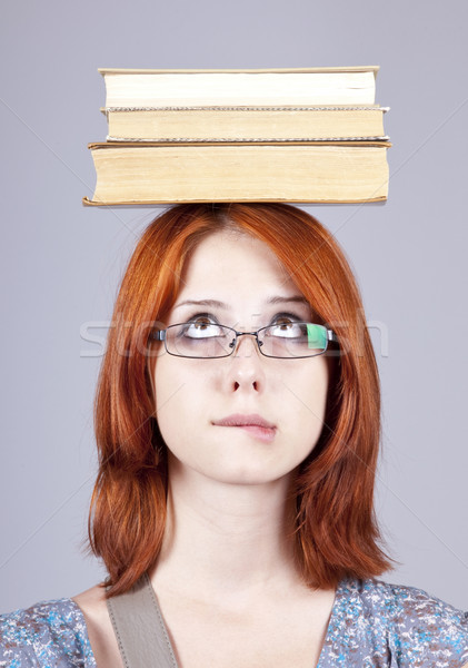 Red-haired girl keep books on her head. Studio shot. Stock photo © Massonforstock