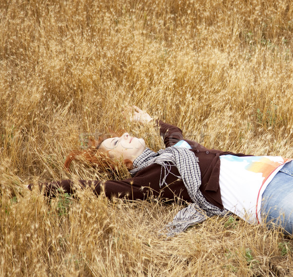 Stock photo: Young beautiful girl lying at yellow autumn field.