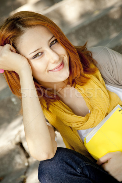 Red-haired student girl with notebook sitting at outdoor. Stock photo © Massonforstock