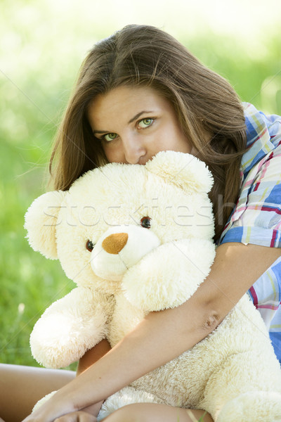 Beautiful teen girl with Teddy bear in the park at green grass. Stock photo © Massonforstock