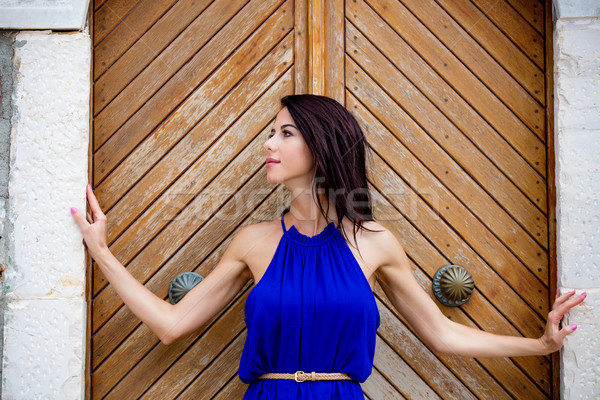 photo of beautiful young woman standing near the wooden old door Stock photo © Massonforstock