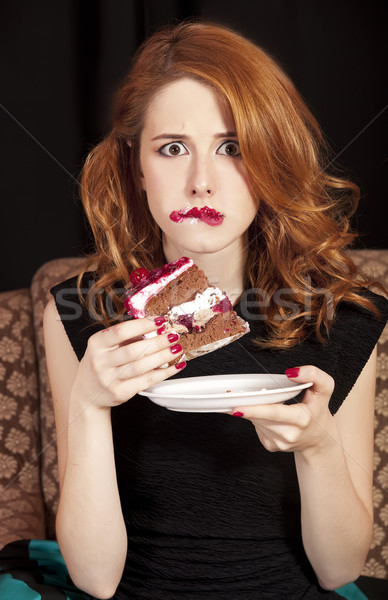 Stock photo: Redhead girl secretly eating cake.