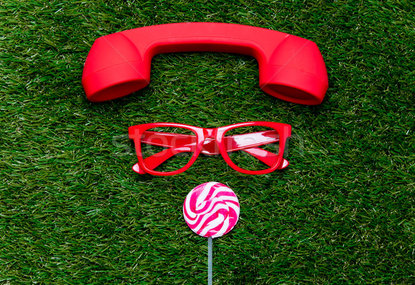 styled red glasses with lollipop and handset on green grass back Stock photo © Massonforstock