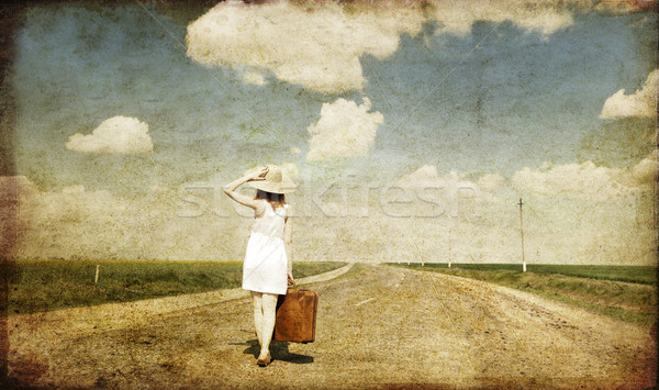 Lonely girl with suitcase at country road. Stock photo © Massonforstock