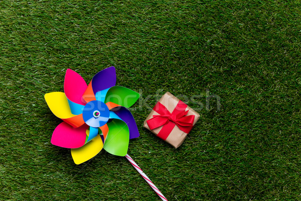Stock photo: Multi colored pinwheel and little gift box on spring green glass