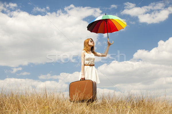 Stock photo: Beautiful redhead girl with umbrella and suitcase at outdoor.