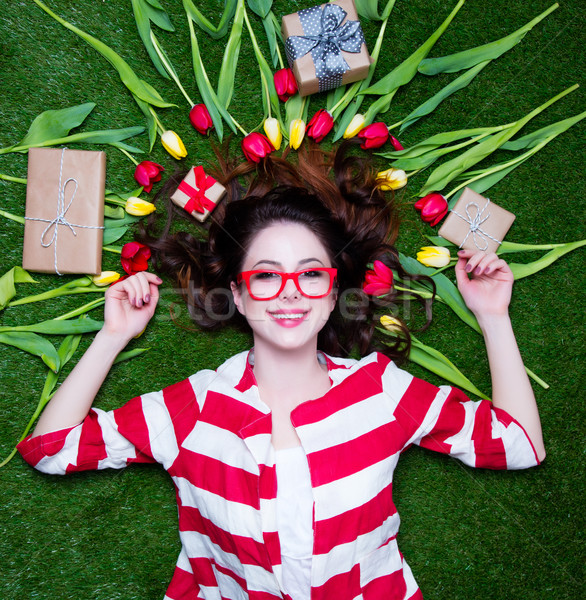 Stock photo: Portrait of a young styled redhead woman with tulips around and 