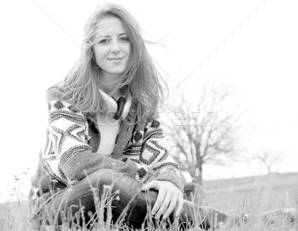 Young fashion girl with headphones sitting at spring meadow. Pho Stock photo © Massonforstock