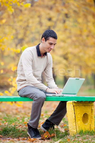 photo of handsome man sitting on the bench with laptop on the wo Stock photo © Massonforstock