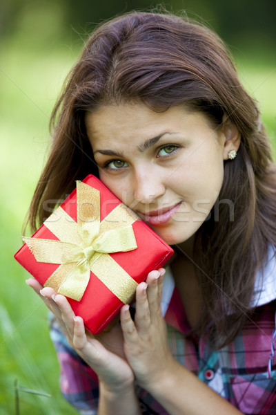 Beautiful teen girl with gift in the park at green grass. Stock photo © Massonforstock