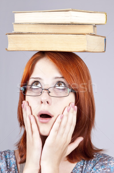 Stock photo: Red-haired girl keep books on her head. Studio shot.