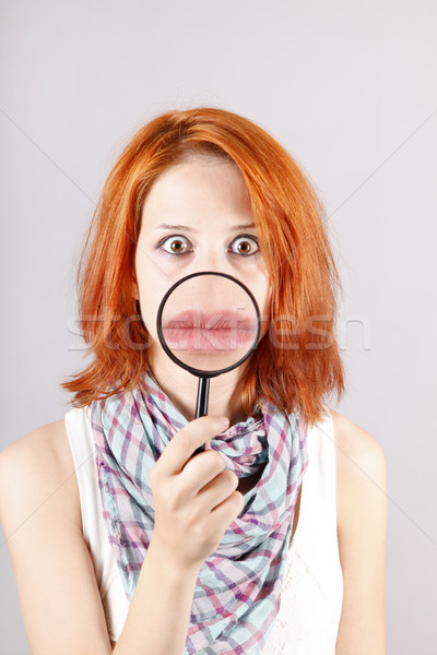 Stock photo: Beautiful red-haired girl with loupe zooming her mouth.