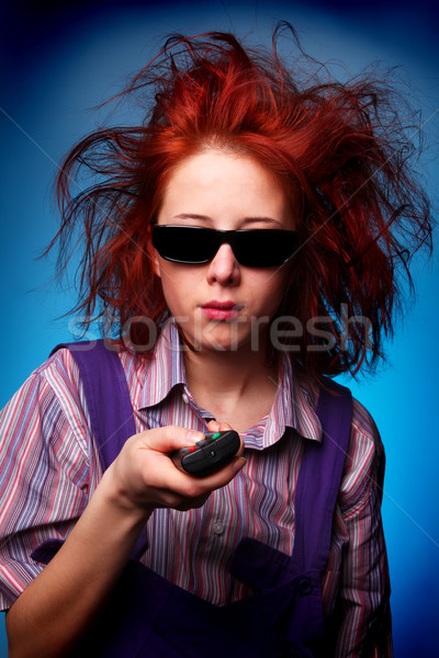 Funny red-haired girl in glasses with TV remote  Stock photo © Massonforstock