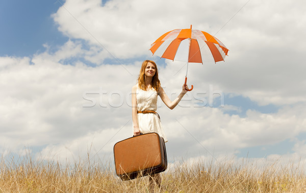 Stock photo: Beautiful redhead girl with umbrella and suitcase at outdoor.