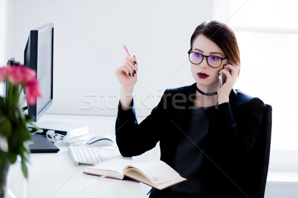 beautiful young woman sitting at the desk and talking on the pho Stock photo © Massonforstock