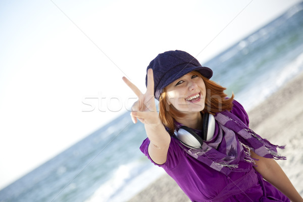 Stock photo: Red-haired girl with headphone on the beach.