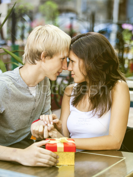 Stock photo: The young man gives a gift to a young girl in the cafe