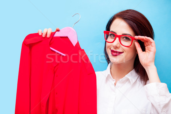 Stock photo: beautiful young woman with shirt on hanger standing in front of 