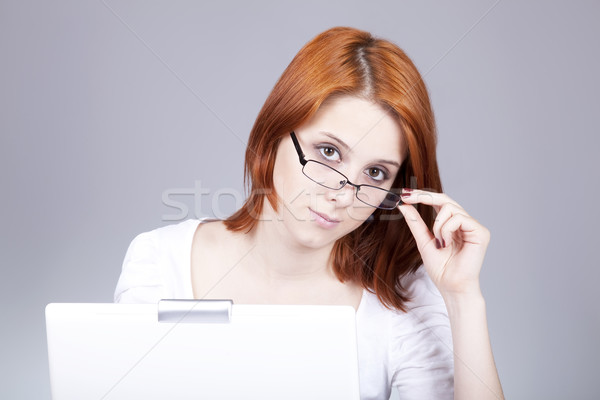 Stock photo: Red-haired girl with white notebook. Studio shot. 