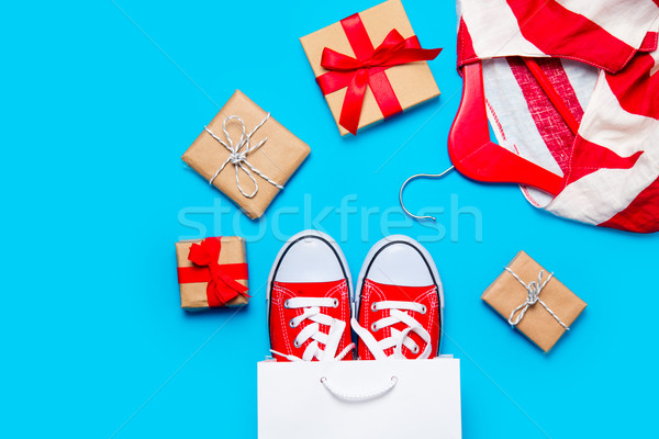 Stock photo: big red gumshoes in cool shopping bag, striped jacket on hanger 