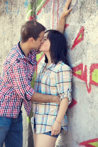 Stock photo: Young couple kissing near graffiti background.