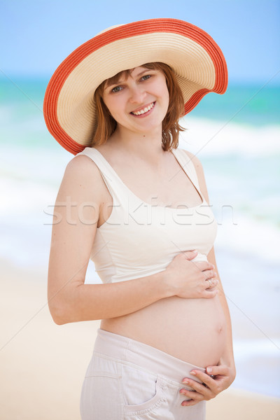 Beautiful pregnant woman at the beach looking happy Stock photo © Massonforstock