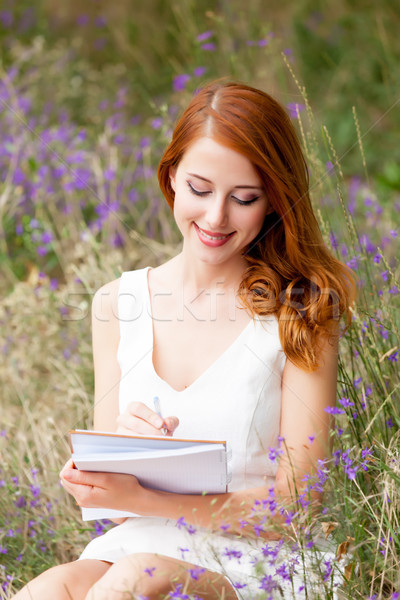 photo of beautiful young woman with copybook sitting on the gras Stock photo © Massonforstock