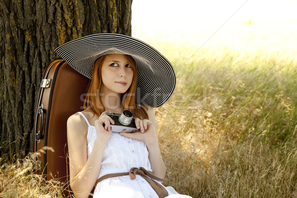 Redhead girl sitting near tree with vintage camera. Stock photo © Massonforstock