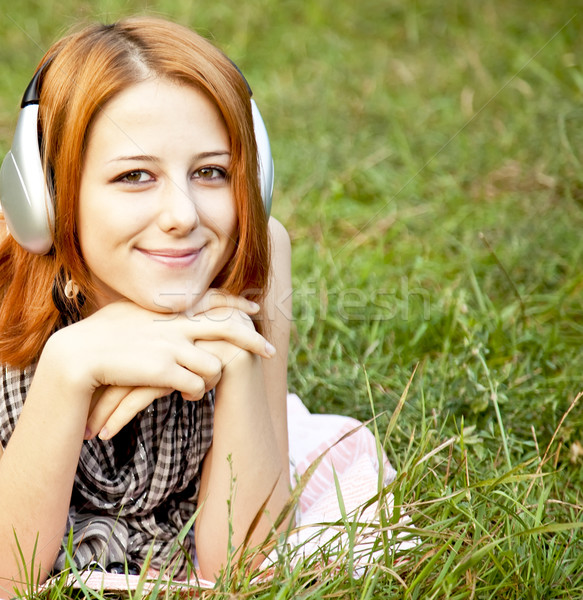 Stock photo: Young fashion girl with headphone lying at green grass
