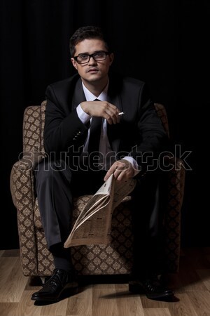 Man with cigarette and newspaper sitting in vintage armchair Stock photo © Massonforstock