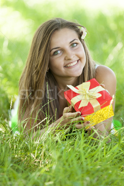 Beautiful teen girl with gift in the park at green grass. Stock photo © Massonforstock