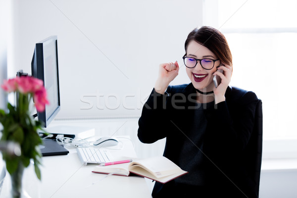 beautiful young woman sitting at the desk and talking on the pho Stock photo © Massonforstock
