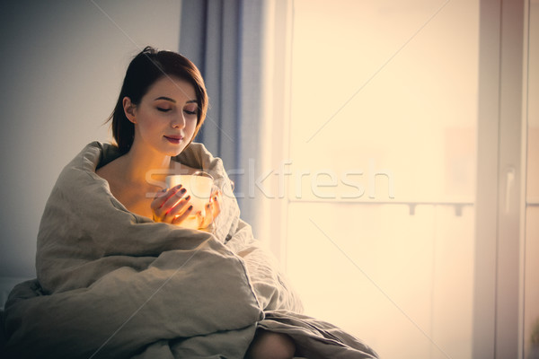 Beautiful rednead woman with cup of coffee or cappuccino in a be Stock photo © Massonforstock