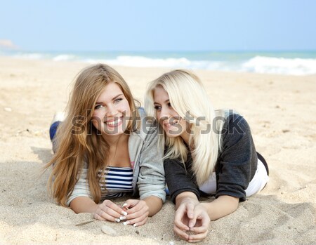 Two girl friends lying down at the beach. Stock photo © Massonforstock