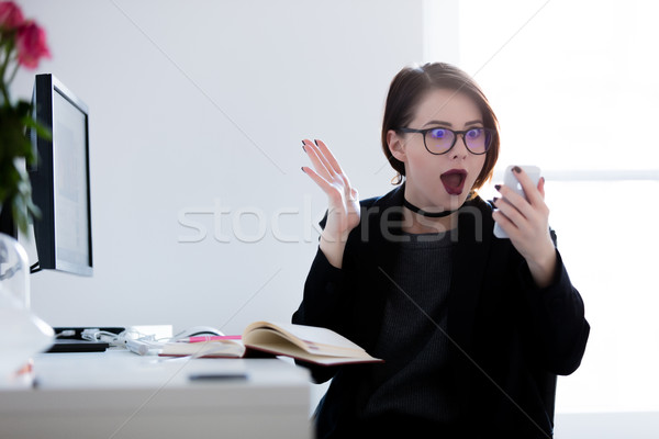 surprised young woman sitting at the desk and looking at the pho Stock photo © Massonforstock