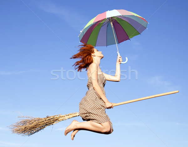 Young red-haired witch on broom flying in the sky with umbrella  Stock photo © Massonforstock
