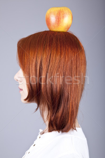 Red-haired girl keep apple on her head. Shot from sideview. Stock photo © Massonforstock