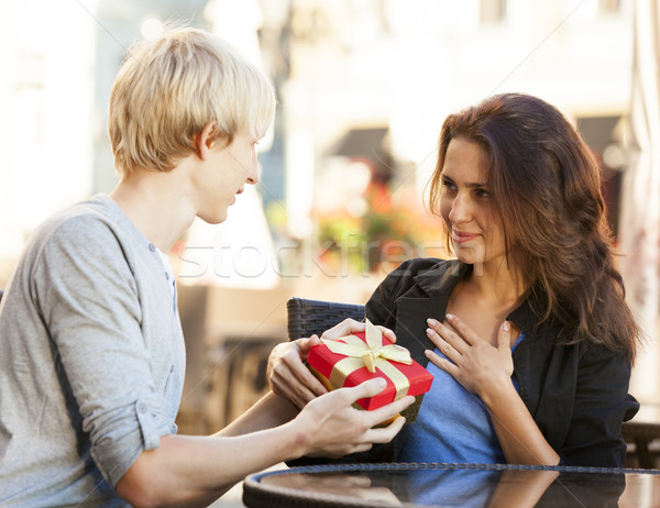 The young man gives a gift to a young girl in the cafe Stock photo © Massonforstock