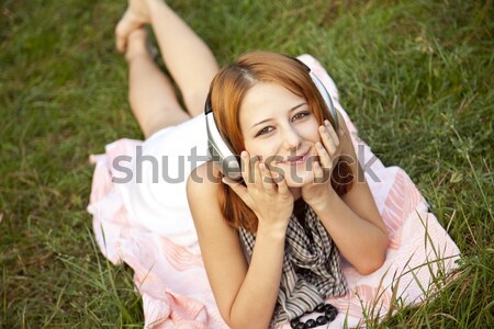 Beautiful red-haired girl at grass with headphones Stock photo © Massonforstock