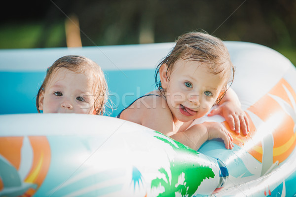 The two little baby girls playing with toys in inflatable pool in the summer sunny day Stock photo © master1305