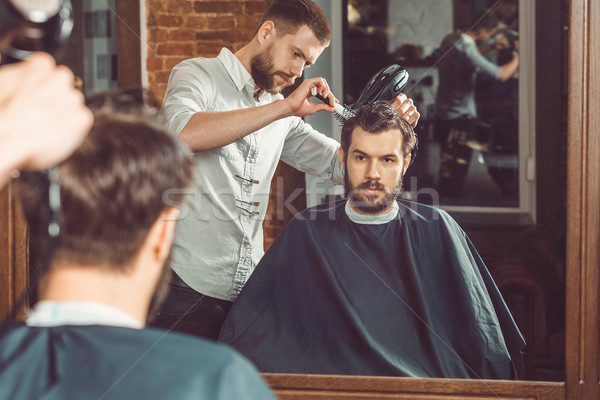 Young handsome barber making haircut of attractive man in barbershop Stock photo © master1305
