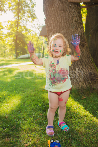 Stock photo: Two-year old girl stained in colors against green lawn