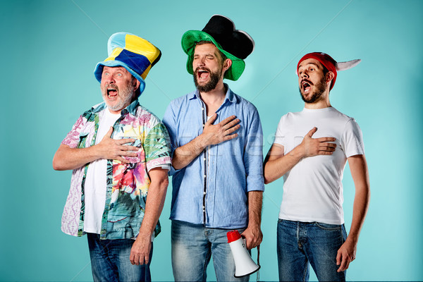 Três futebol fãs cantando hino azul Foto stock © master1305