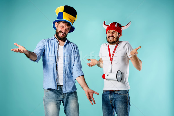 Stock photo: The two football fans with mouthpiece over blue