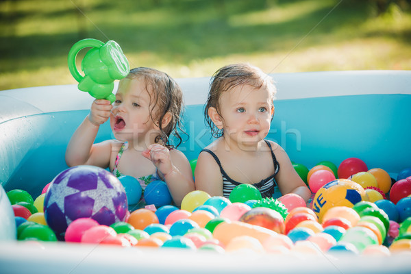 The two little baby girls playing with toys in inflatable pool in the summer sunny day Stock photo © master1305