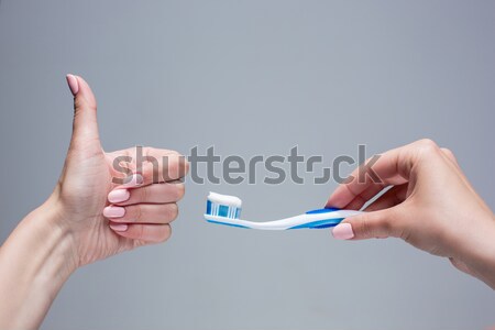 Stock photo: Toothbrush in woman's hands on gray