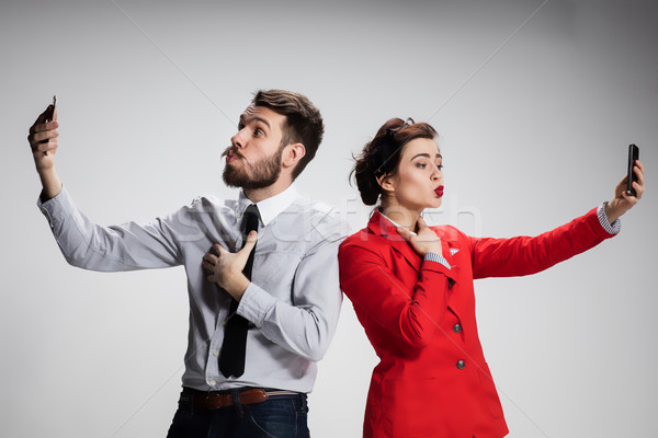 Stock photo: Business concept. The two young colleagues holding mobile phones on gray background