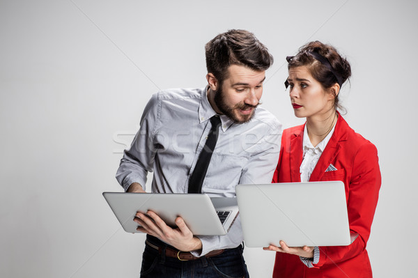 The young businessman and businesswoman with laptops communicating on gray background Stock photo © master1305