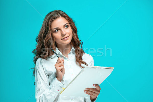 The smiling young business woman with pen and tablet for notes on blue background Stock photo © master1305