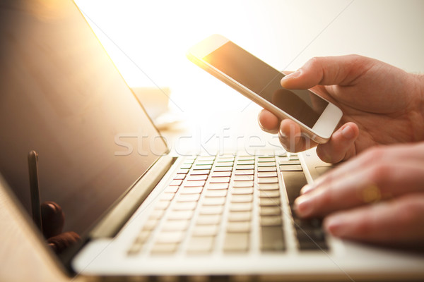 Férfi kéz tart telefon iroda laptop Stock fotó © master1305